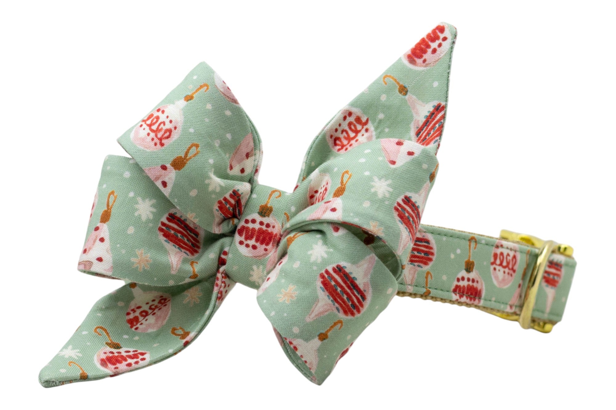 Holiday dog collar with an attached statement belle bow in soft mint green fabric printed with vintage-style ornaments and winter snowflakes. The bow is voluminous and dramatic, with pleated loops and long pointed ends, giving the collar a bold, cheerful look. Finished with polished metal hardware.